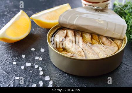 Geräucherter Sprotte mit Öl in einer offenen Blechdose auf dunklem Hintergrund, Nahaufnahme. Stockfoto