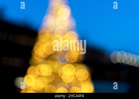 Weihnachtsbaum mit Lichterketten auf blauem Hintergrund. Stockfoto