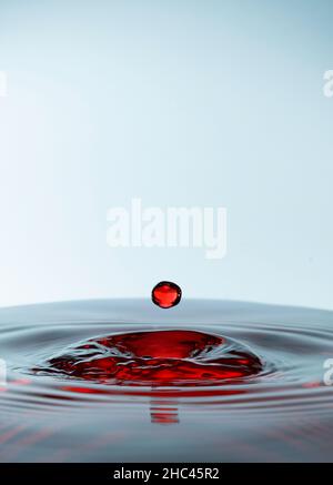 Wassertropfen spritzt rot, isoliert auf weißem Hintergrund. Stockfoto