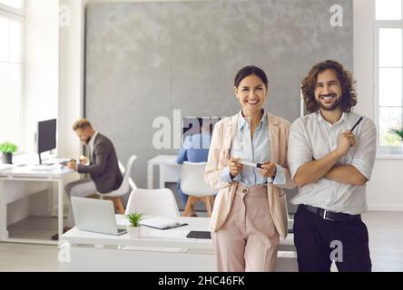 Porträt zweier glücklicher Geschäftspartner einer Frau und eines Mannes, die in einem modernen Coworking Center stehen. Stockfoto