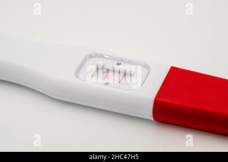 Positiver Schwangerschaftstest in Nahaufnahme auf weißem Hintergrund Stockfoto