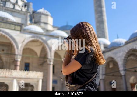 Braunhaarige Touristenfrau, die an einem sonnigen Tag in İstanbul die Suleymaniye-Moschee fotografiert. Reisen und aktiver Lifestyle, Sommerurlaubskonzept. Stockfoto