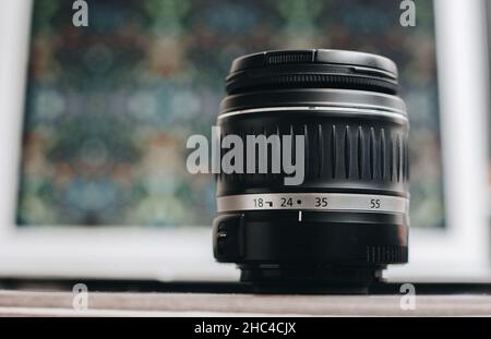 Nahaufnahme eines Fotoobjektivs mit Bokeh-Hintergrund auf dem Tisch. Stockfoto