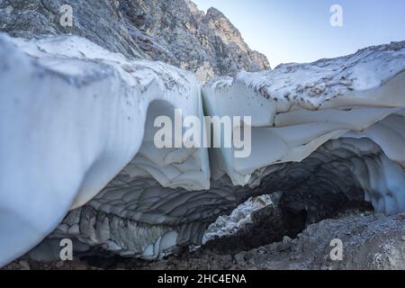 Höhle unter einem Schneegletscher in den Bergen Stockfoto