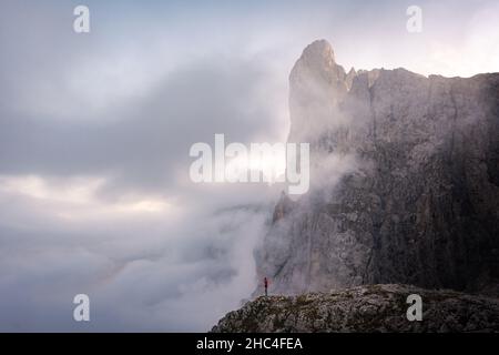 Mann, der am Rande einer Klippe in den Bergen von Pale di san martino in den dolomiten, umgeben von Wolken, steht Stockfoto