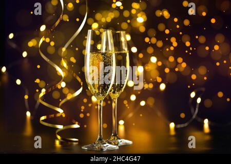 Zwei Sektgläser auf dunklem Hintergrund mit Weihnachtsbeleuchtung Stockfoto