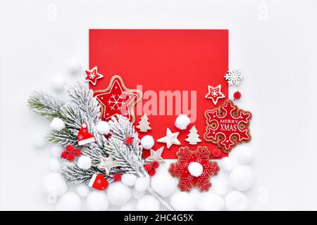 Fichtenzweig im Schnee mit weihnachtlichen Dekorationen auf weißem und rotem Hintergrund. Grußkarte zu Weihnachten oder Neujahr. Stockfoto