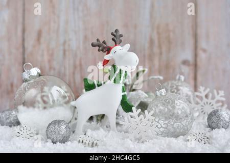 Weihnachtsschmuck kleine Figur Elch mit festlichen Dekorationen оn den Schnee. Grußkarte zu Weihnachten oder Neujahr. Stockfoto