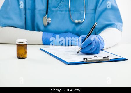 Nahaufnahme einer jungen Ärztin, die an ihrem Schreibtisch im Krankenhaus arbeitet, einer Allgemeinpraktikerin, die im Büro sitzt und ein Rezept für Medikamente schreibt, einer Frau Stockfoto
