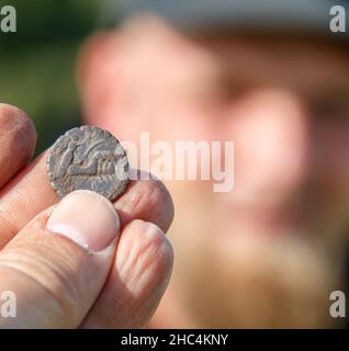 Bronzezeit-Pinzette mit einem Metalldetektor gefunden, Finder im Hintergrund Stockfoto