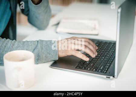 Büromitarbeiter, der in seinem Büro auf der Laptop-Tastatur tippt, Mann, der auf dem Laptop arbeitet. Nahaufnahme der Hände auf dem Laptop. Hochwertige Fotos Stockfoto
