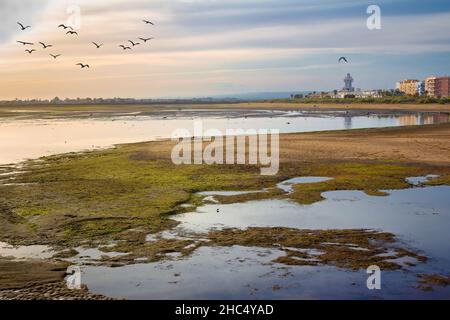 Panoramablick auf den Strand von La Gaviota bei Ebbe mit dem Leuchtturm von Isla Cristina im Hintergrund. Existiert in: Huelva, Andalusien, Spanien Stockfoto