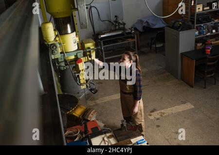 Großansicht des lächelnden Schweißers, der mit dem Schweißgerät im Werk arbeitet Stockfoto