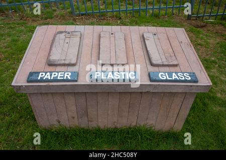 Recycling-Behälter für den Außenbereich aus Kunststoffplanken, die Holzplanken nachahmen. Papierglas und Kunststoff können von diesem Behälter aufgenommen werden Stockfoto