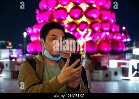 Hongkong, China. 24th Dez 2021. Ein Paar macht ein Selfie bei einer Weihnachts-Installationsbaum in Hongkong. (Foto von Miguel Candela/SOPA Images/Sipa USA) Quelle: SIPA USA/Alamy Live News Stockfoto
