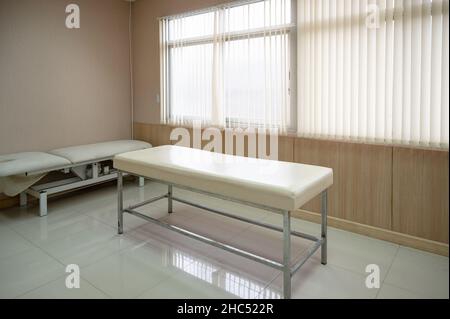 Leeres Patientenauskultationsbett mit Sonnenlicht, das auf den Vorhang in der Station im Krankenhaus scheint Stockfoto