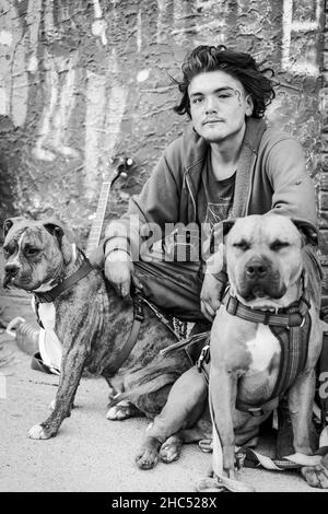 Vertikale Graustufenaufnahme eines Obdachlosen und seines Hundes auf einer Straße in Moose Jaw, Kanada Stockfoto