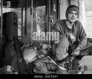 Graustufenaufnahme eines Obdachlosen und seines Hundes auf einer Straße in Moose Jaw, Kanada Stockfoto