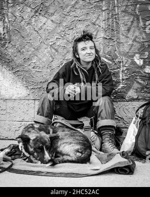 Graustufenaufnahme einer obdachlosen Frau und seines Hundes auf einer Straße in Moose Jaw, Kanada Stockfoto