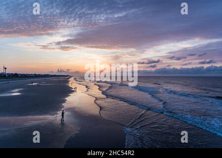 Wunderschöne Landschaft am Strand mit plätschernden Wellen unter dem wolkigen Sonnenuntergangshimmel Stockfoto