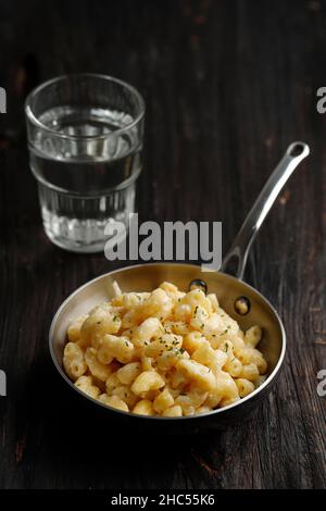 Mac und Käse, Macaroni-Pasta im amerikanischen Stil mit kitschiger cremiger Sauce und zerkleinertem Semmelbrösel auf dem dunklen rustikalen Tisch Stockfoto