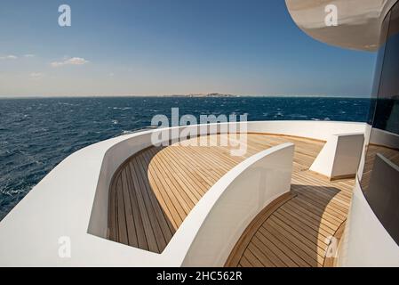 Blick vom Teakholz-Bugdeck auf eine große Luxus-Motoryacht mit tropischem Meerblick im Hintergrund Stockfoto