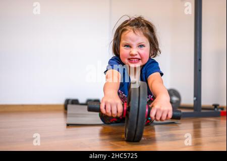 Ein vier Jahre altes Mädchen macht Calisthenics Training in der Heimsporthalle. Stockfoto