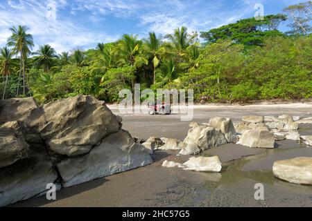 Geländefahrrad, das auf einem felsigen Strand von Costa Rica vor einem Palmenhintergrund steht Stockfoto