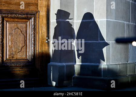 Weingarten, Deutschland. 24th Dez 2021. Kinder spielen die Weihnachtsgeschichte auf dem Vorplatz der St.-Martin-Basilika. Die Schatten von Maria und Joseph sind an der Wand der Basilika zu sehen. Mehr als 200 Menschen beobachten im Regen. Quelle: Felix Kästle/dpa/Alamy Live News Stockfoto