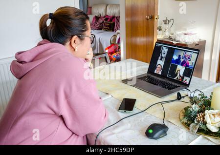 Eine asiatische Dame plaudert mit der Familie bei einem Telefongespräch auf einem Laptop. Stockfoto