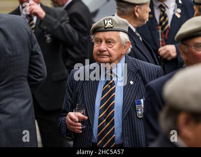 Veteranen-Soldaten mit einem älteren Mann, der eine Baskenmütze trägt und bei einer Versammlung, Royal Mile, Edinburgh, Schottland, Großbritannien, einen Drink hält Stockfoto