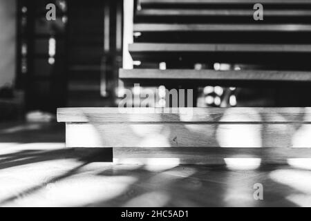 Selektive Fokusaufnahme von Holztreppen und Schatten darauf in Schwarz-Weiß-Farben Stockfoto