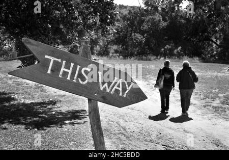 Zwei Besucher folgen den Wegweisern zu den Attraktionen des Wohnkomplexes El Rancho de las Golondrinas in der Nähe von Santa Fe, New Mexico. Stockfoto