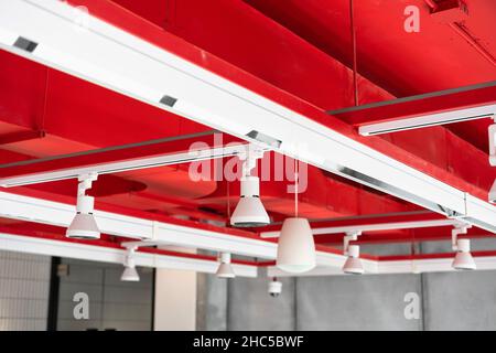An der Decke montierte, kassettenartige Klimaanlagen mit anderen Teilen des Belüftungssystems (Rohre, Kabel und Lüftungsschlitze) in der Geschäftshalle mit Stockfoto