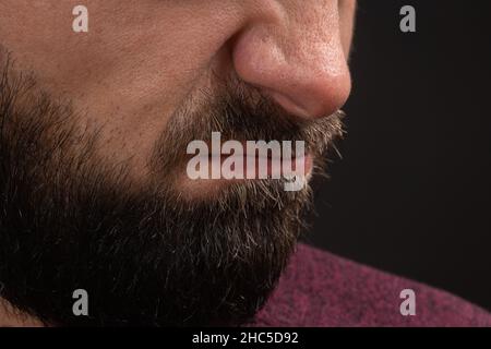 Faltige Grimasse der Gefahr, Nahaufnahme auf Gesicht und Lippen eines jungen, nicht erkennbaren Mannes mit schwarzem Bart und Schnurrbart, Konzept von Wut und Wut Stockfoto