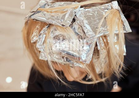 Friseur macht Bouffant mit Kamm auf dünnen Strähnen. Shatush Technik für Haaraufhellung Stockfoto