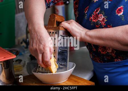 Nahaufnahme einer älteren weißen Frau, die Käse rostet Stockfoto