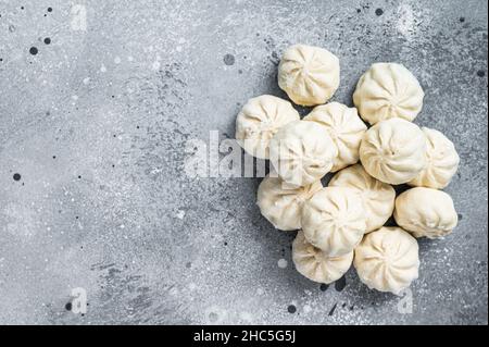 Gefrorene, ungekochte Baozi-Knödel, gefüllt mit Fleisch. Grauer Hintergrund. Draufsicht. Speicherplatz kopieren Stockfoto