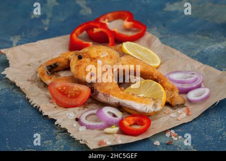 Weihnachtskarpfen, gebratene Karpfenfischscheiben auf Papier Gebratene Fischfilets aus goldener Kruste mit Zitrone und Gemüse. Stockfoto