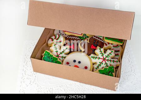Vielfalt von Weihnachtszucker-Keksen in einer Pappschachtel auf weißem Deckchen auf weißem isoliert Stockfoto