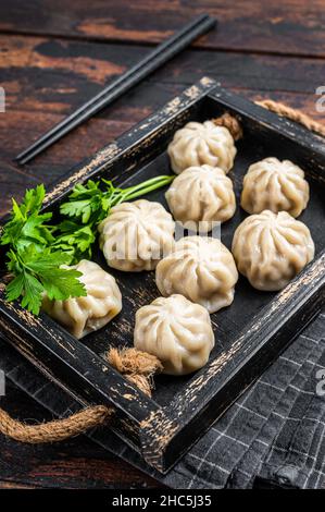 Momo Knödel in einem Holztablett mit Kräutern. Dunkler Holzhintergrund. Draufsicht Stockfoto