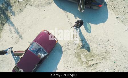 Luftaufnahme auf Räuber mit Gewehren geschossen das Auto und verlassen. Terrorist oder Autodieb, der mit einer Waffe auf den Fahrer zeigt. Ein bewaffneter Mann in der Maske drohende Pis Stockfoto