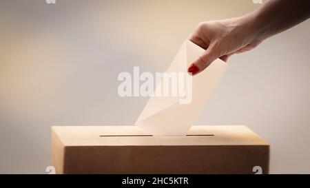 Auswahlkonzept. Eine Wählerin wirft ihren Stimmzettel an die Wahlurne Stockfoto