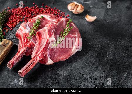 Rohe Tomahawk Rib Kalbssteaks auf Fleischspalter. Schwarzer Hintergrund. Draufsicht. Speicherplatz kopieren Stockfoto