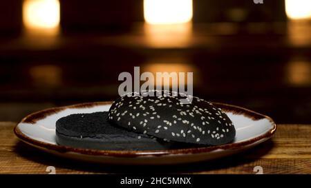 Nahaufnahme einer Reihe von Burgerbrötchen ohne Zutaten, die auf drei Tellern auf dunklem Raum liegen, Kochkonzept. Sandwichbrötchen in verschiedenen Farben Stockfoto