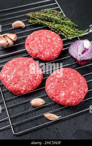 Rohes Rindfleisch aus biologischem Anbau, runde Patties für hausgemachten Burger. Schwarzer Hintergrund. Draufsicht Stockfoto