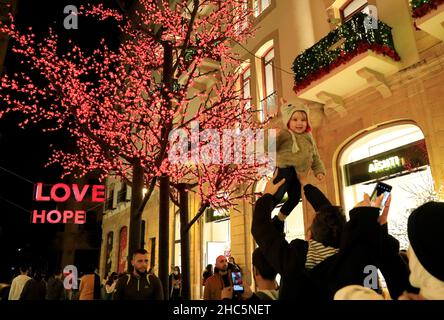 Beirut, Libanon. 24th Dez 2021. Am 24. Dezember 2021 zieht ein Mann ein Kind für ein Foto mit Weihnachtsschmuck in der Innenstadt von Beirut, Libanon, auf. Quelle: Liu Zongya/Xinhua/Alamy Live News Stockfoto