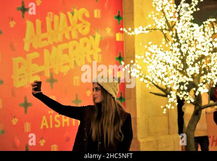 Beirut, Libanon. 24th Dez 2021. Eine junge Frau macht am 24. Dezember 2021 ein Selfie mit Weihnachtsschmuck in der Innenstadt von Beirut, Libanon. Quelle: Liu Zongya/Xinhua/Alamy Live News Stockfoto