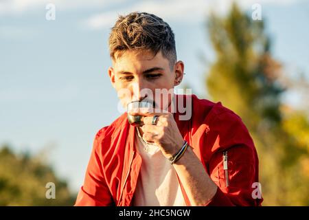 Porträt eines Mannes, der draußen Tee aus dem Glas der Thermo trinkt Stockfoto