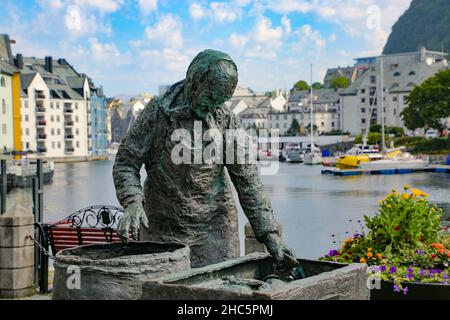 Sildekona (Herringfrau oder Fischdame) Statue mit einem der Kanäle mit Booten und Jugendstilgebäuden im Hintergrund, Alesund, Norwegen. Stockfoto